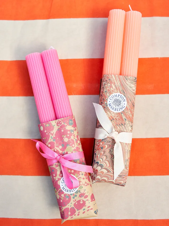 two sets of scalloped dinner candles, each with a marbled paper wrapping and ribbon