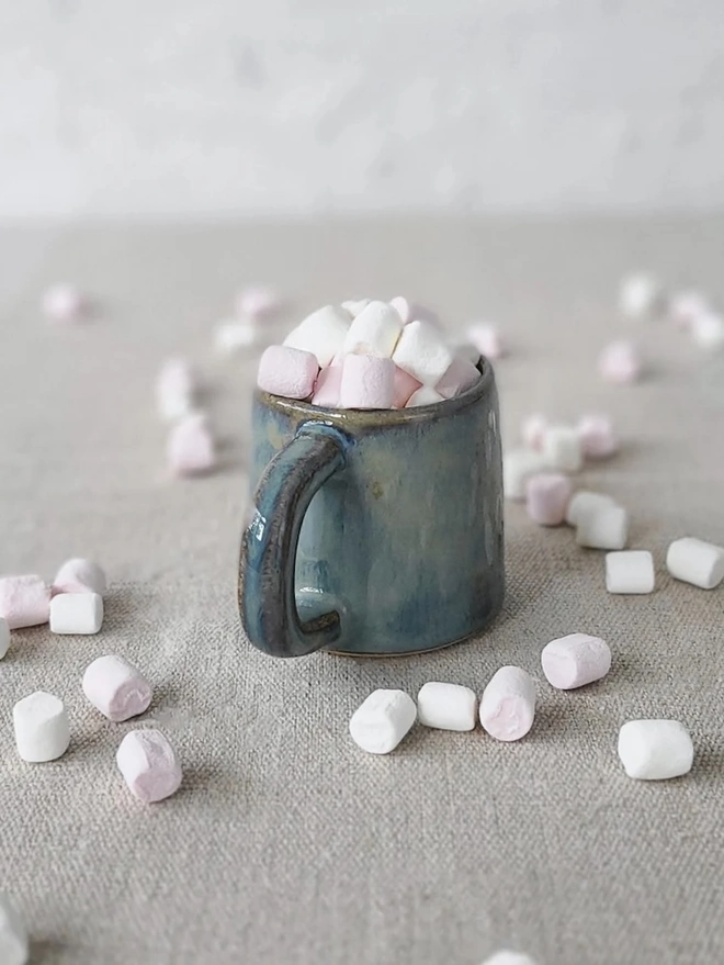 Classic Ceramic Espresso Mug, a colourful ceramic espresso mug sitting on a plain surface against a white backdrop. It is accompanied by a group of marshmallows. 