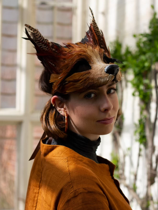 Woman wearing a luxury red fox masquerade mask atop her head as a headdress
