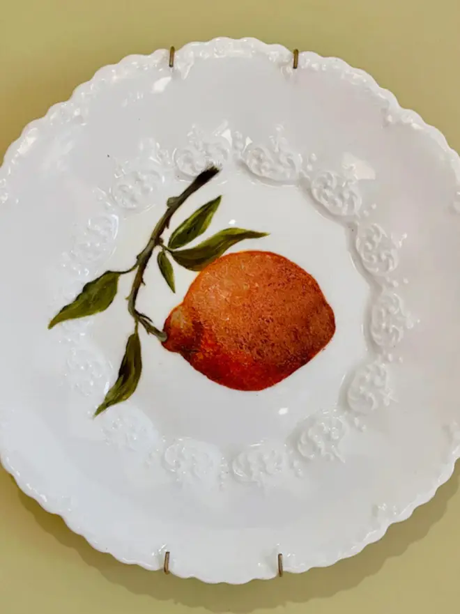 Oil Painted Orange On Antique Plate against a yellow background. 