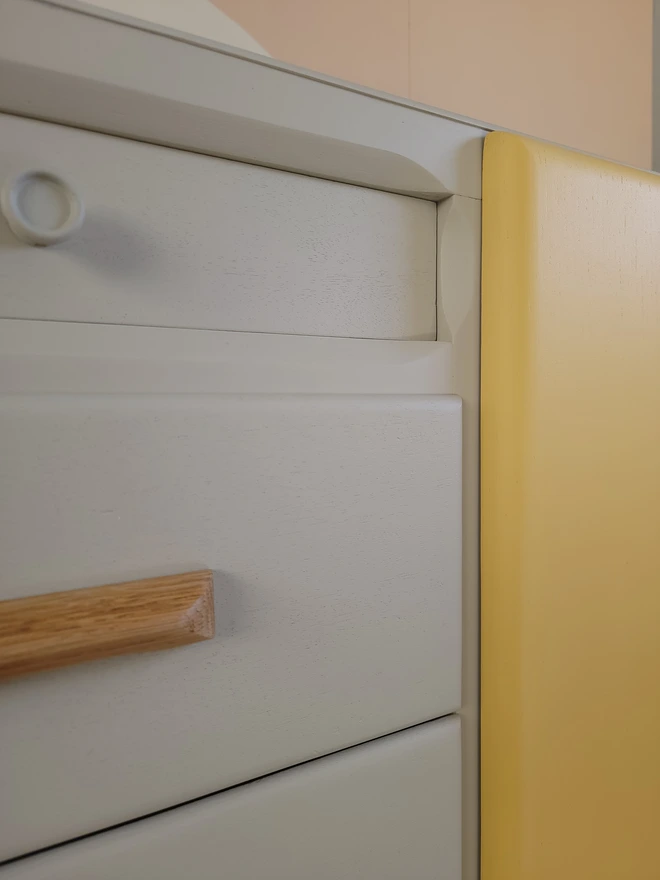Close up of putty painted drawers and yellow cupboard door