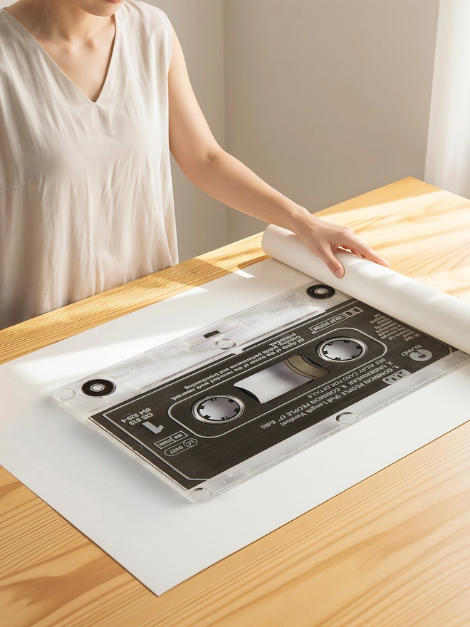 Pulp 'Common People' cassette tape print. print being unrolled on wooden table.