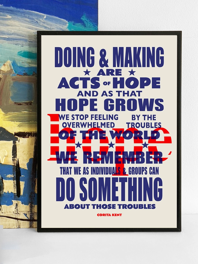 Framed multicoloured typographic print of “Acts Of Hope”  The print rests against a blue and yellow abstract painting.