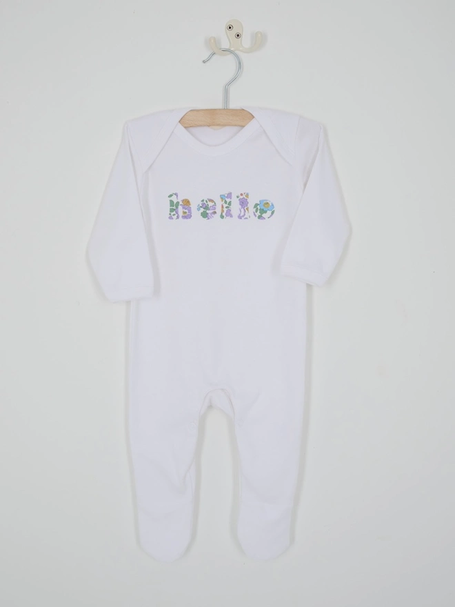 a white cotton romper with hello sewn onto it in a floral betsy liberty print. close up of the appliqué stitching