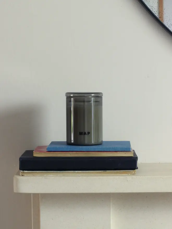 blue fields lavender and sandalwood candle. candle stacked on top of book pile.