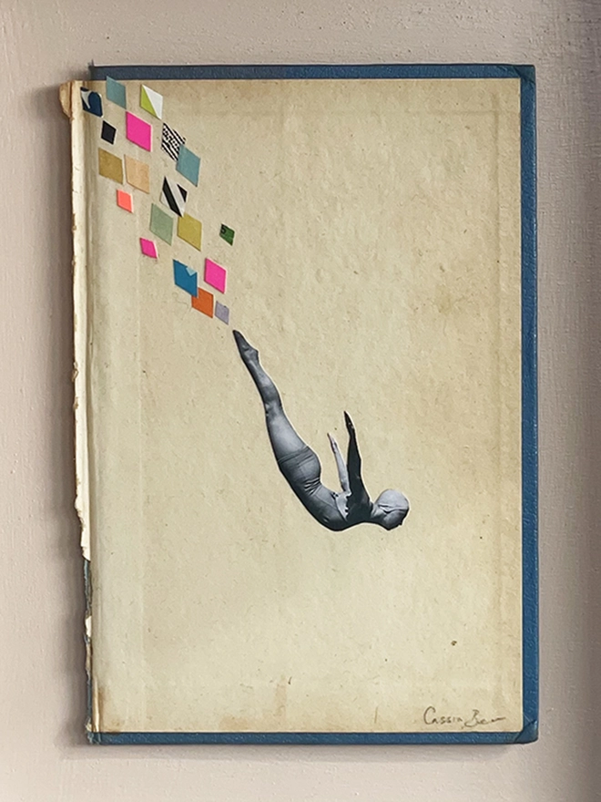 A female swimmer performs the perfect swan dive into the swimming pool below. A framed collage made with vintage papers and pops of neon pink with torn edges and interesting textures.
