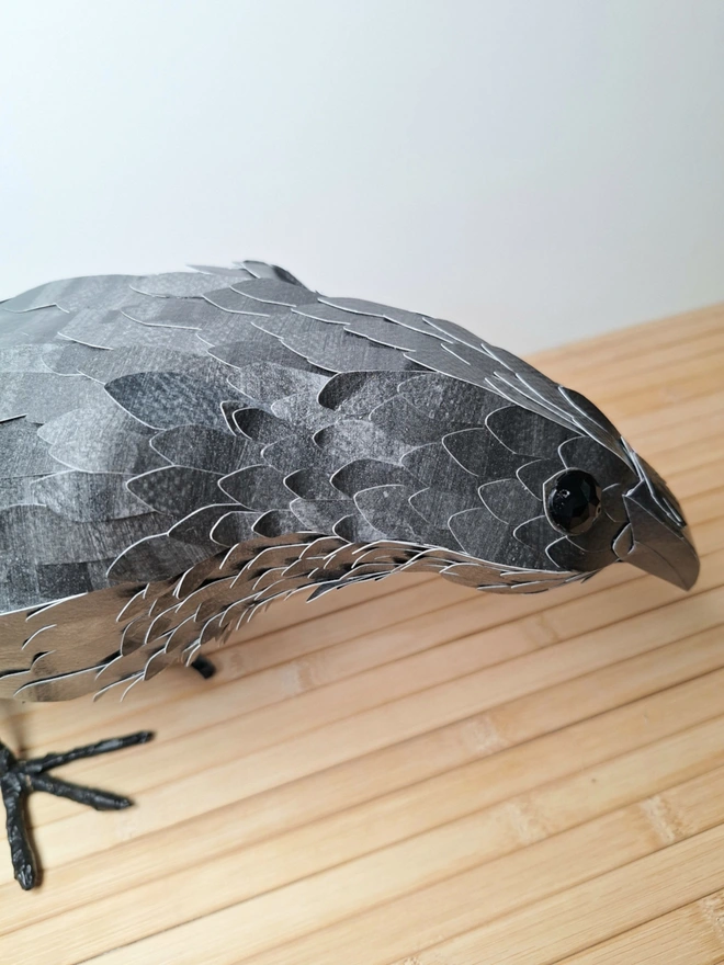 side view of a raven sculpture, with a close up of his individually cut feathers