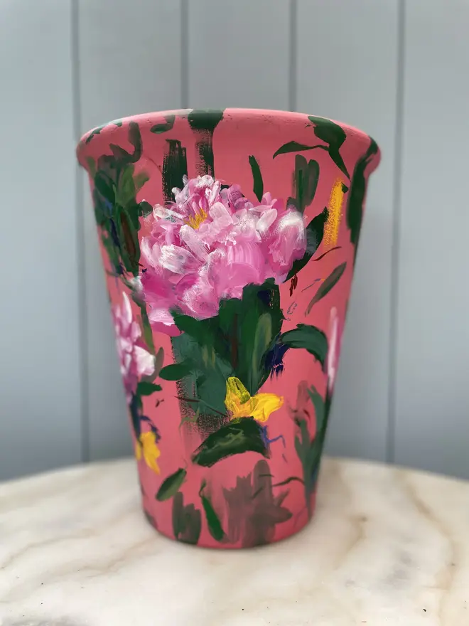 Unique hand-painted terracotta pot featuring pink peonies on a red background