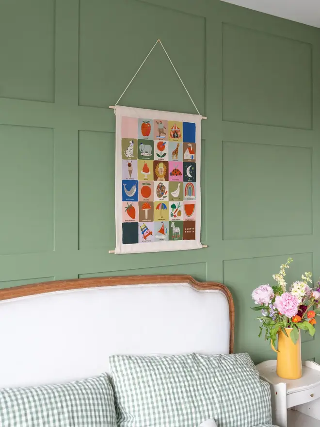 Colourful Rainbow Alphabet Fabric Banner, hanging on a green wall. 