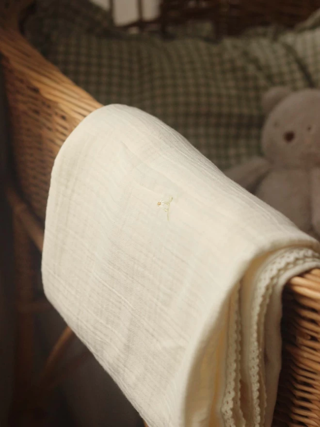 Folded muslin blanket in wild chamomile design hanged on a changing basket