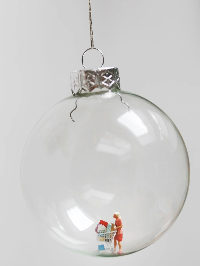 Miniature figure of a woman shopping, in a glass Christmas bauble 