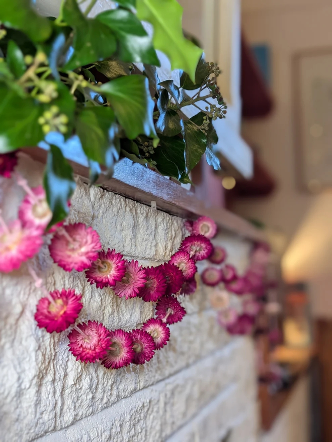 pretty pinks dried flower garland. pink dried flower garland hung along white brick wall.
