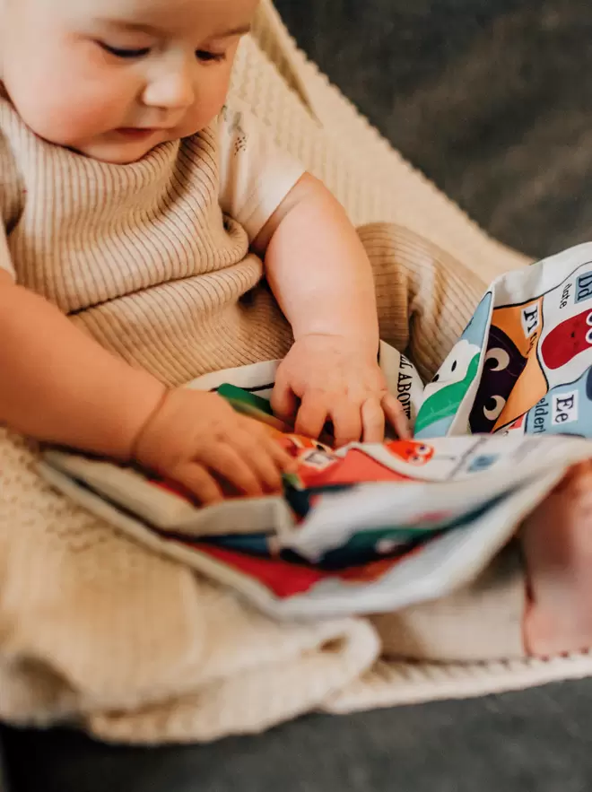 Baby looking down and touching the crinkly cloth book