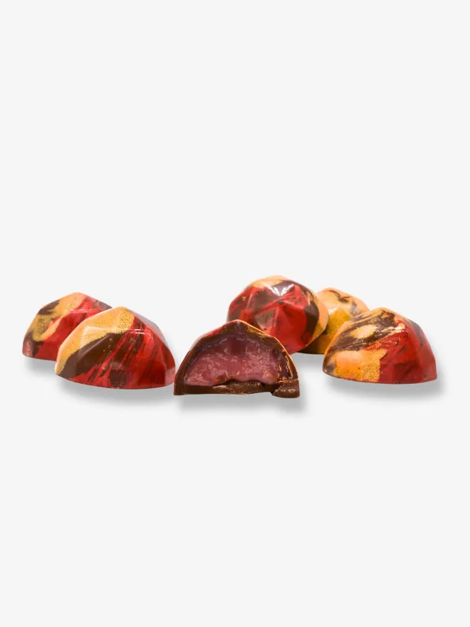 6 luxury milk chocolates with one cut in half revealing a raspberry rose filling