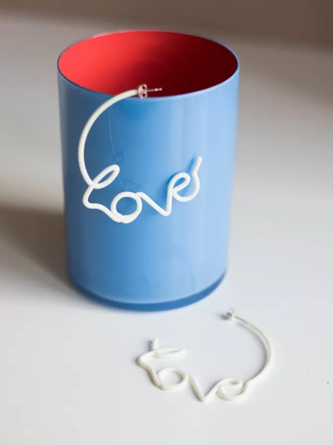 Large white Love Hoops by Zoe Sherwood seen in a blue cup with a red inside.