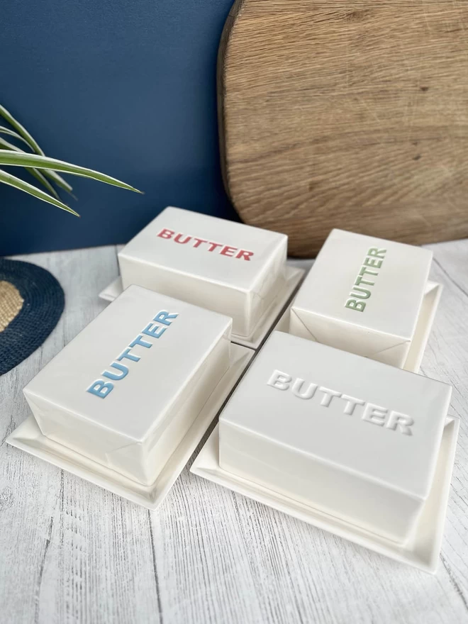 4 handmade butter dishes showing the different colours the lettering can be in - blue, red, green or plain.