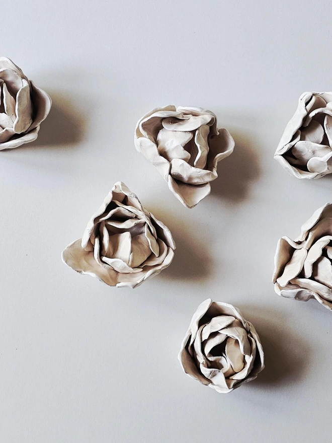 hand-sculpted ceramic flower in a soft cashmere glaze, featuring individually crafted petals and natural texture. Each unique piece is wall-mountable with a carved keyhole on the back