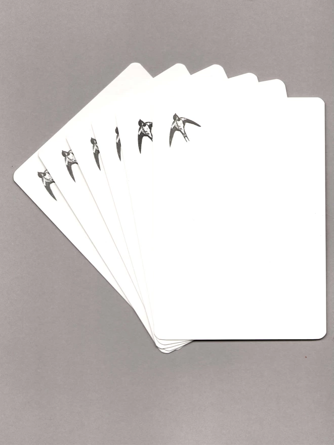 Six notecards with black flowers at the top laid out on a grey background