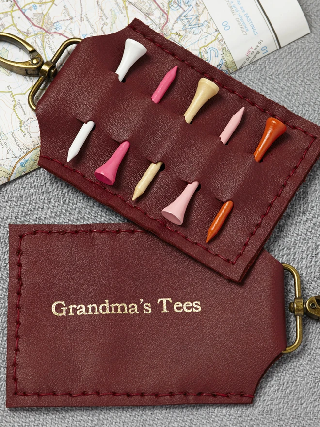 Dark Red leather golf tee holder, featuring gold lettering and wooden golf tees.