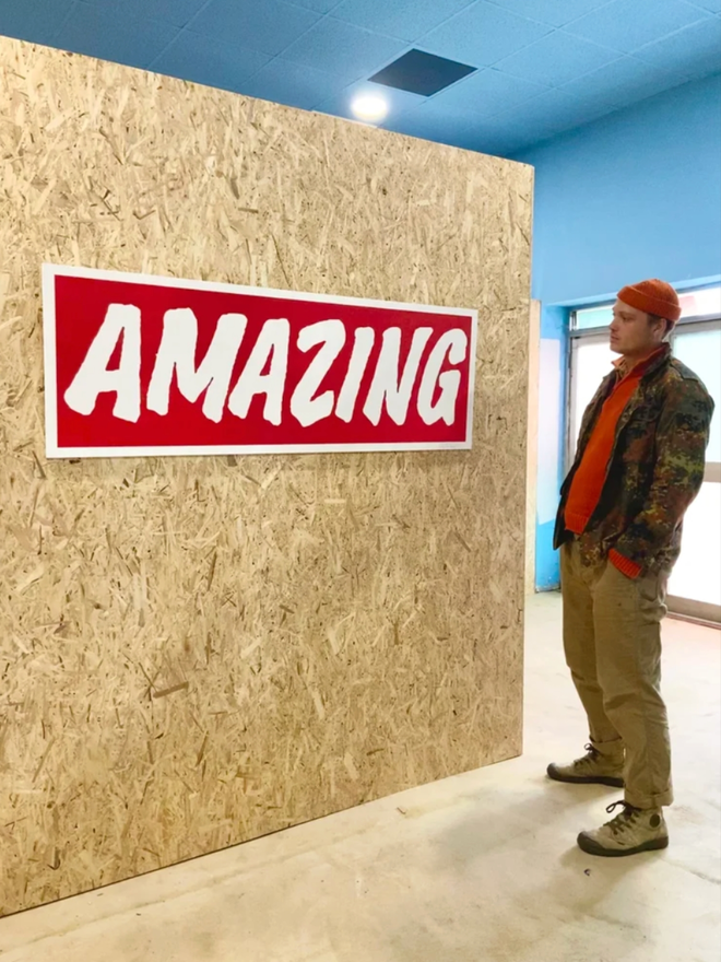 Very Big Amazing. The print shown against a wall. A person is stood in front of it.