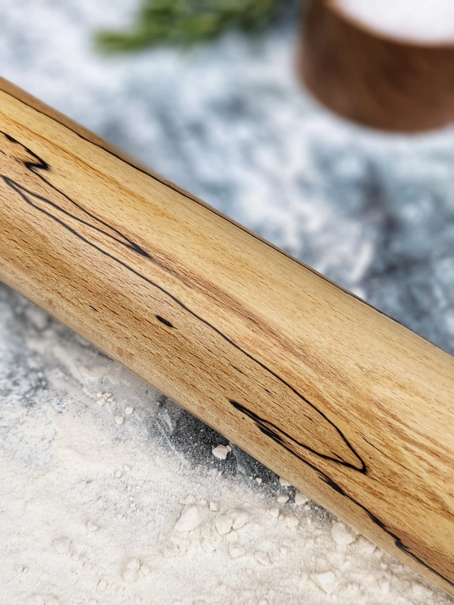 Close up of a stunning hand made rolling pin in Spalted Beech by Something From The Turnery, the picture is focussed on the black lined all natural detailing along the centre of the rolling pin.