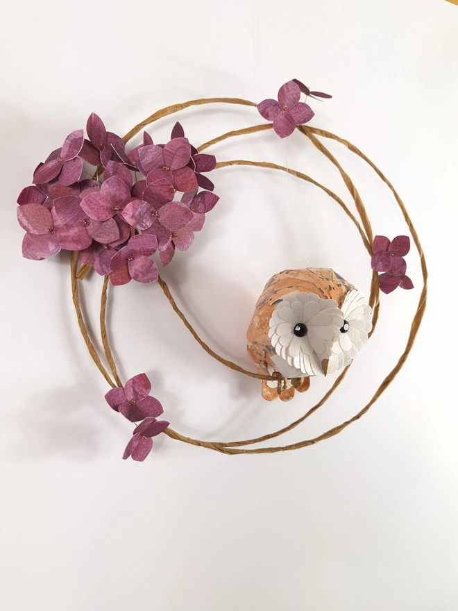 side view of a woodland wall sculpture, featuring a barn owl baby, perched on a wreath of mulberry hydrangea