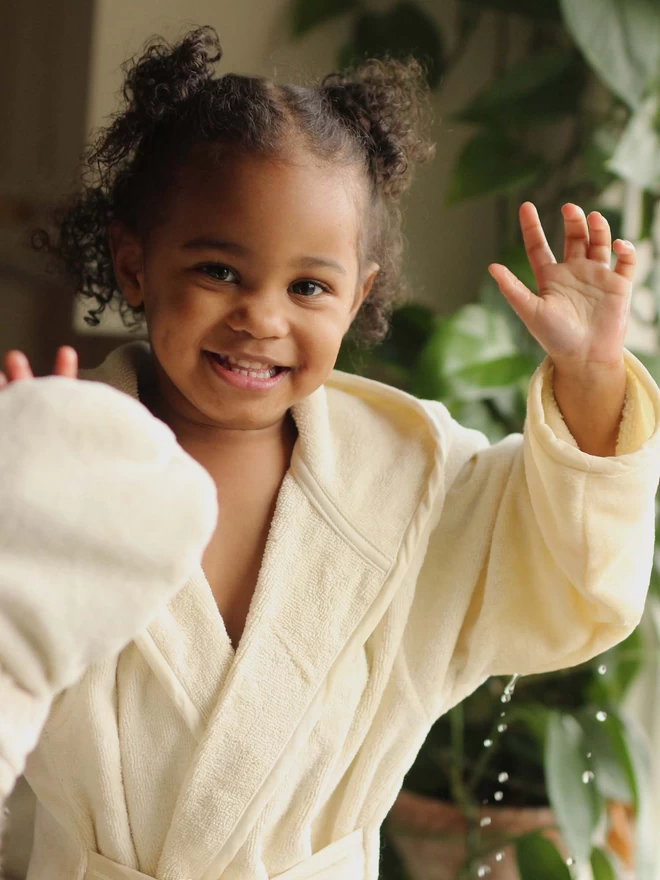 A girl playing wearing a towelling robe splashing water