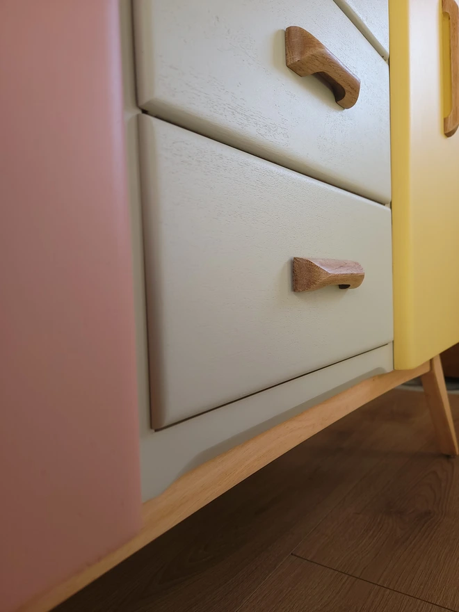 Stripped wood tapered legs on painted mid-century sideboard painted pink, beige and yellow