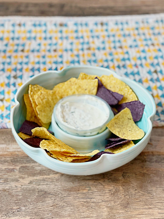 flower shaped chip and dip bowl on table with tortilla chips and dip