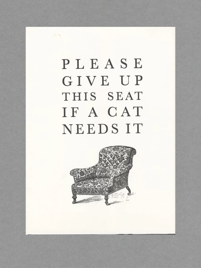 Poster with a black armchair and black text reading 'Please Give Up This Seat If A Cat Needs It' on white paper