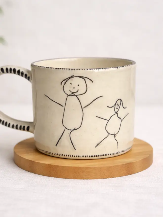 Ceramic mug with a child's drawing of two stick men figures