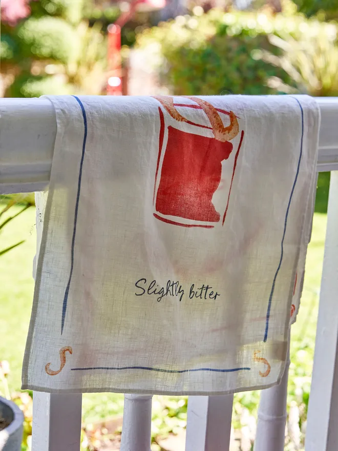 Negroni - Slightly Bitter Linen Tea Towel, resting on the wooden fence 