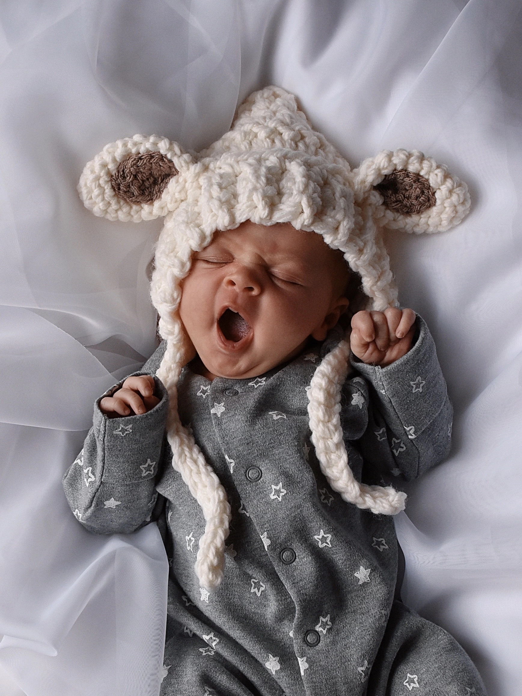 Newborn wearing a handmade crochet lamb bonnet