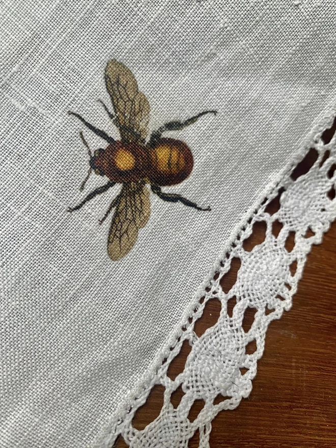 Close up of lace table runner with hand printed bee