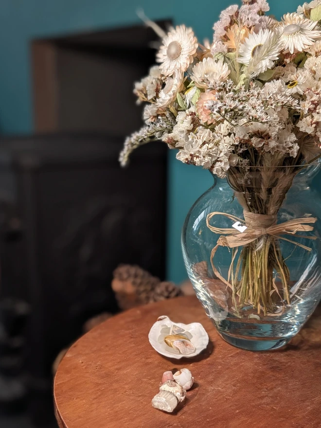 seashell dried flower bouquet. white and neutral coloured dried flower bouquet in a round glass vase.
