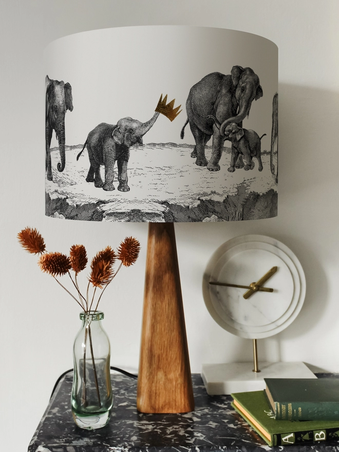Drum Lampshade featuring elephants on a wooden base on a shelf with books and ornaments