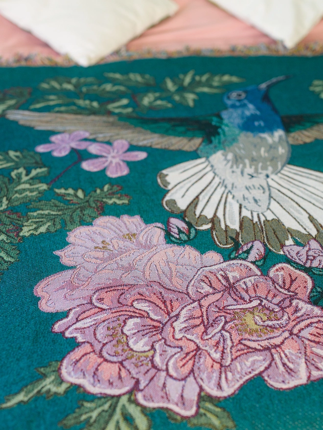 Joy Hummingbird Woven Blanket on bed