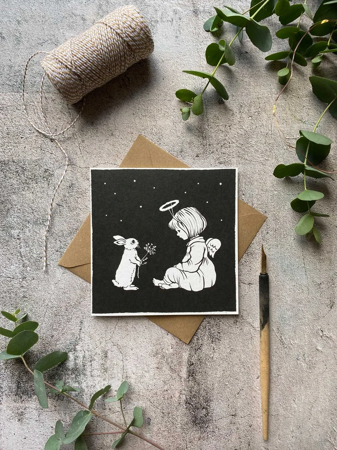 a greeting card featuring my vintage illustration of a child angel and a bunny sat in a wintery nights