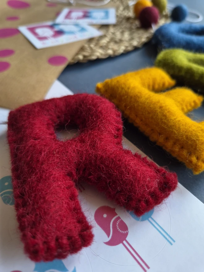 A close up of a dark red letter R laid on a table. Which is part of a garland that says 'Read'.