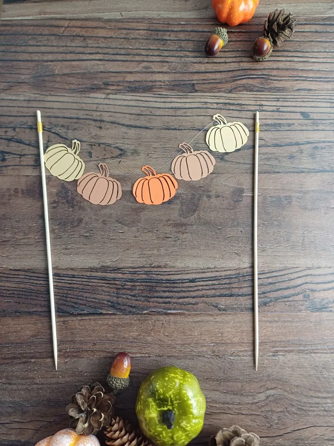 Pumpkin cake topper laid flat on wooden table, pumpkin decorations are displayed in order: Honey Brown, Cinnamon Brown, Orange, Cinnamon Brown, Honey Brown