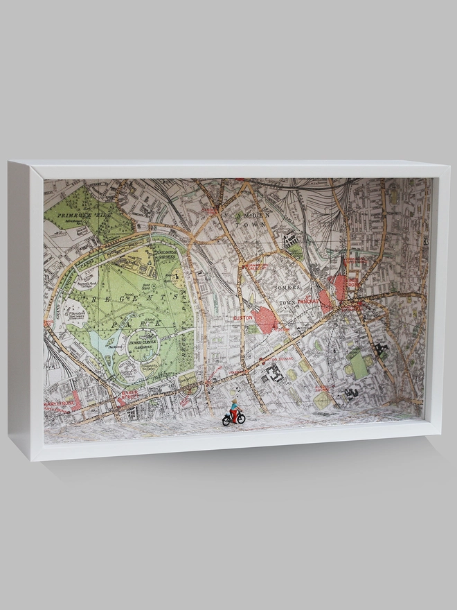 Artbox comprising a tiny figure on a bike cycling against sparkling map backdrop  (whole artwork)