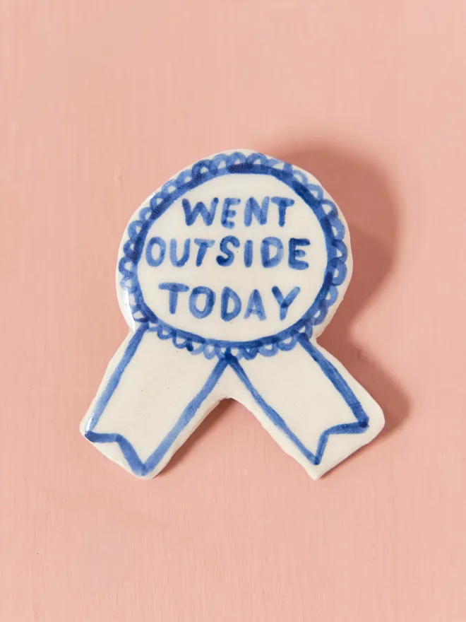  Blue Handmade Ceramic Award, a blue and white ceramic award badge sitting on a pink surface