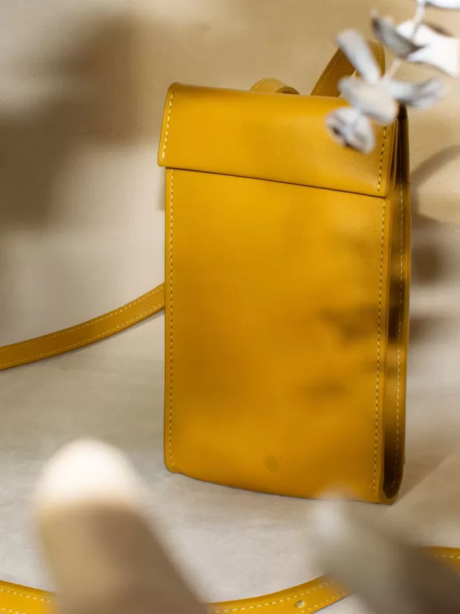 Amber Yellow Phone Bag styled between dried leaves 
