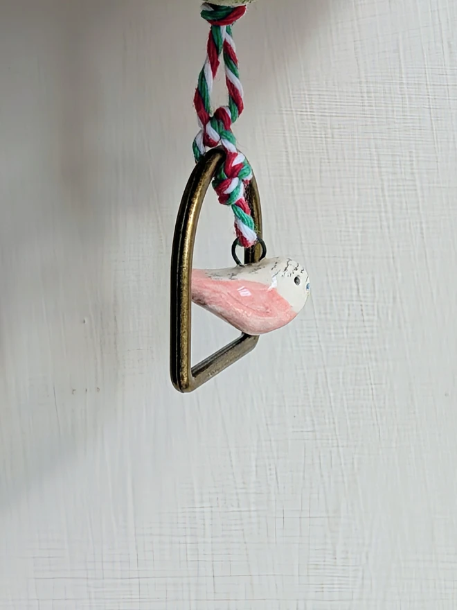 budgie bell with pink bird hanging from the bottom