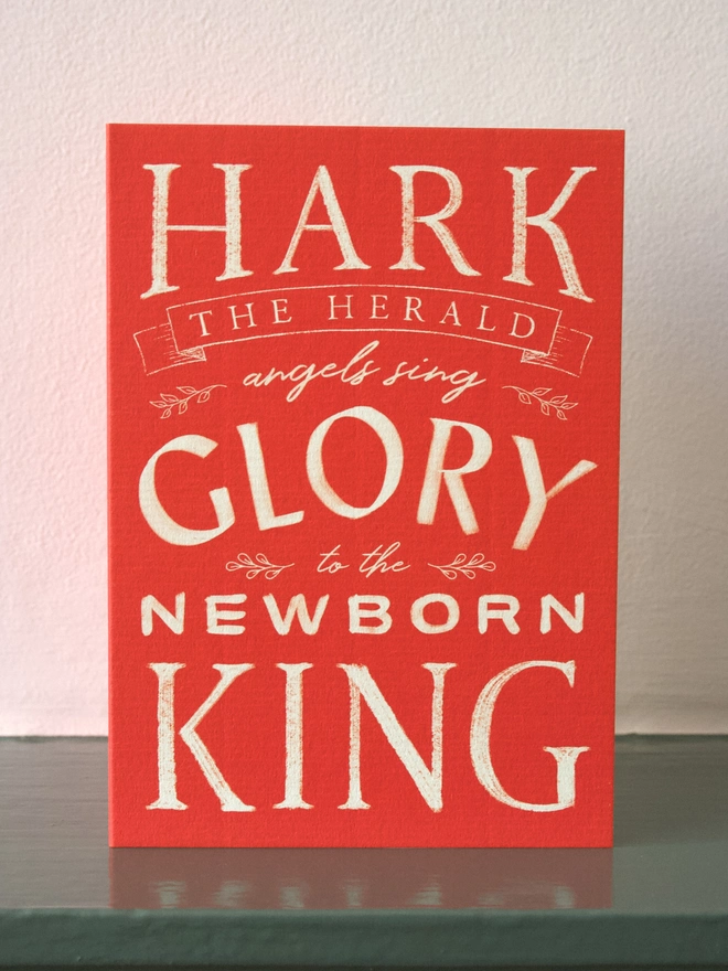 Red Christmas card with carol words from Hark the herald angels sing