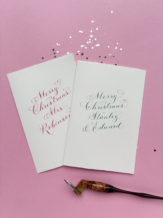 Set of 2 Christmas cards in red and green calligraphy, shown with a fancy wooden calligraphy pen