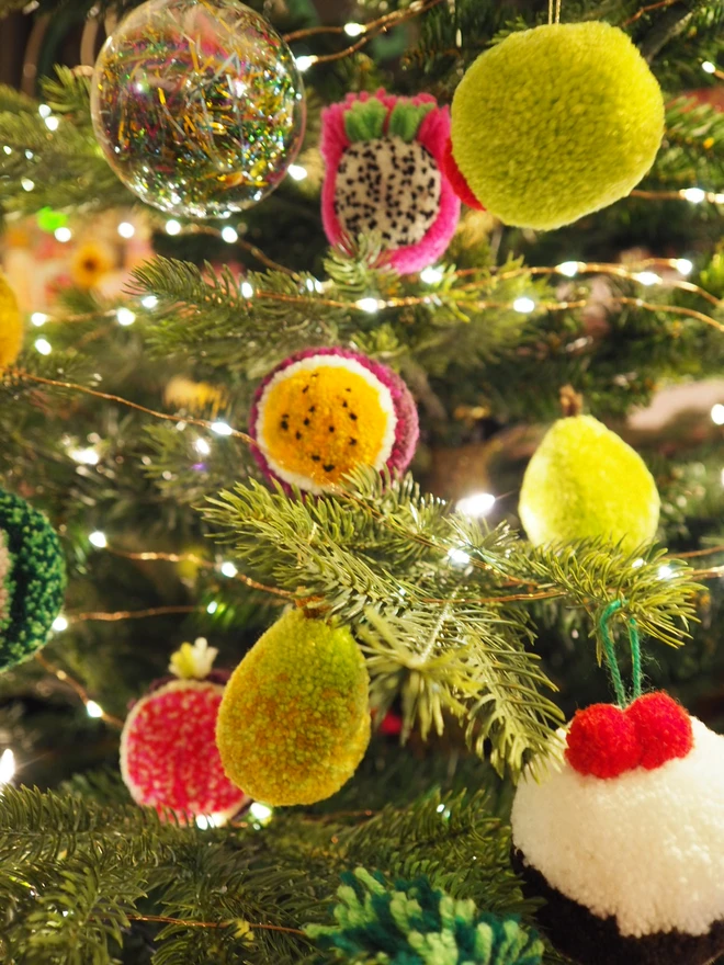 Handmade Passionfruit Pom Pom Bauble hanging on a tree with other pom pom baubles