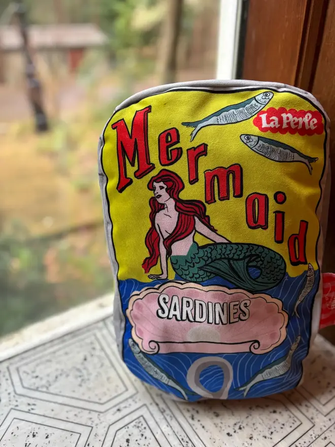 Mermaid Tin Cushion, a decorated mermaid cushion sitting on a window sill. 