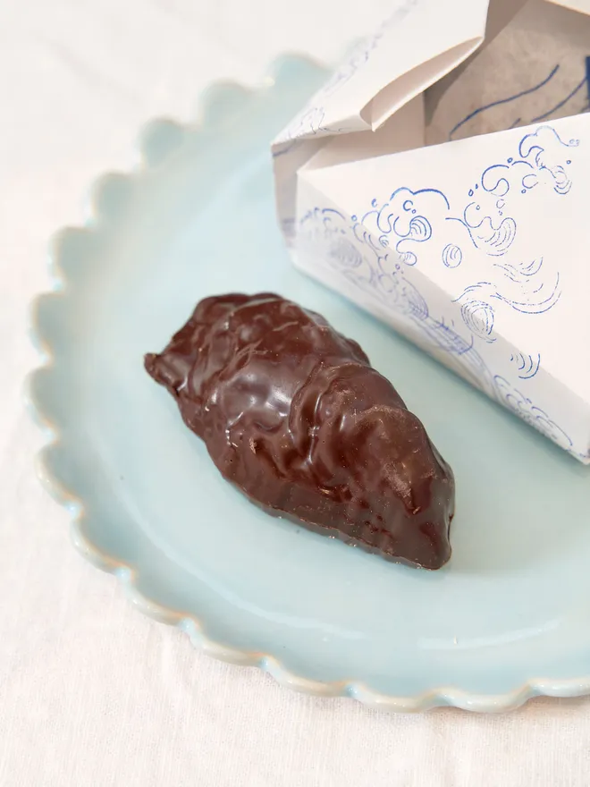 chocolate oyster on blue plate, with white box