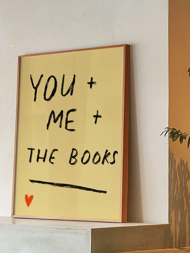 Print leans up against wall, yellow background with handwritten text 'You and me and the books'